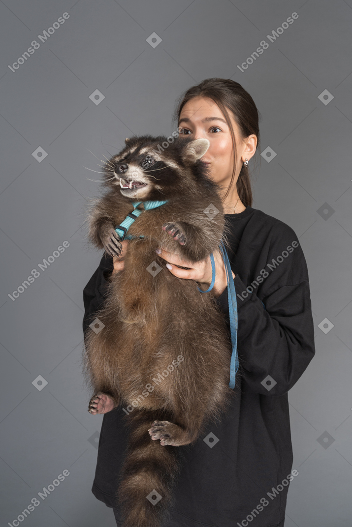 Young woman holding raccoon