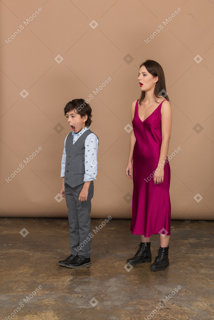 Mulher sonolenta com vestido vermelho e menino com colete cinza
