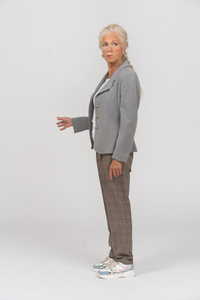 Vista lateral de una anciana en traje mirando algo