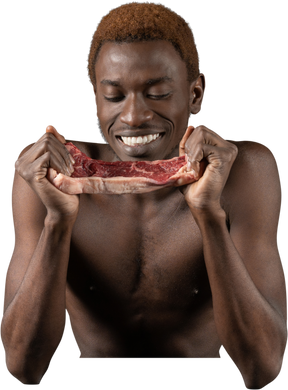 Vista frontal de um homem afro sorridente olhando para uma fatia de carne