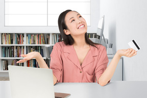 A woman sitting at a laptop with credit card