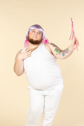 Dreamy looking young overweight man dressed as a fairy holding fairy wand