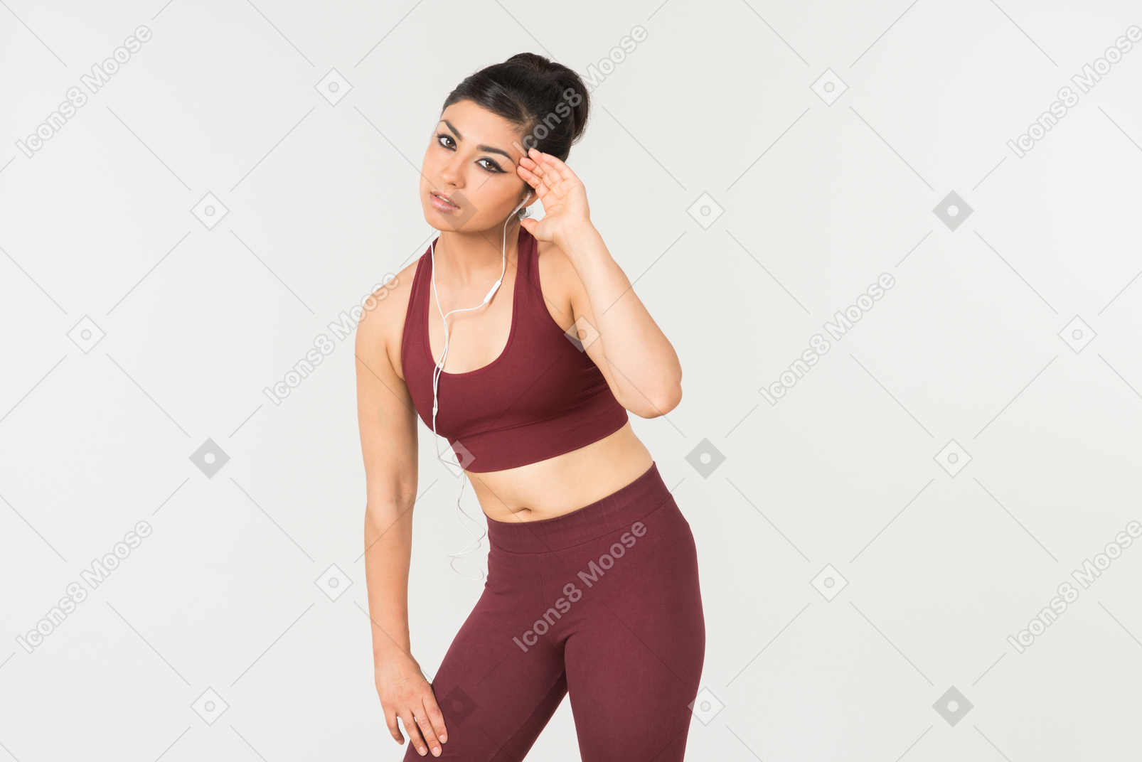 Tired looking young indian woman in sporstwear standing with headphones on her neck