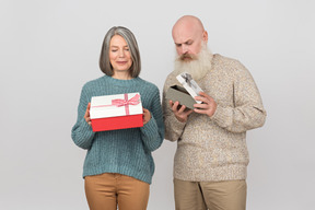 Elegante pareja de ancianos dando regalos el uno al otro