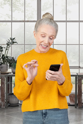 A woman in a yellow sweater looking at a cell phone