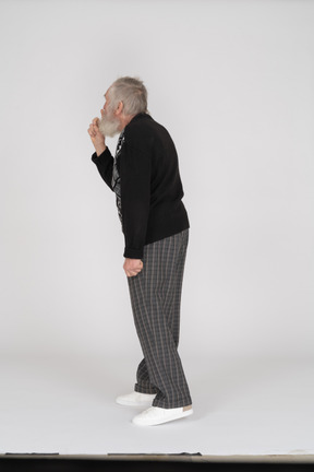 Side view of old man showing silence gesture