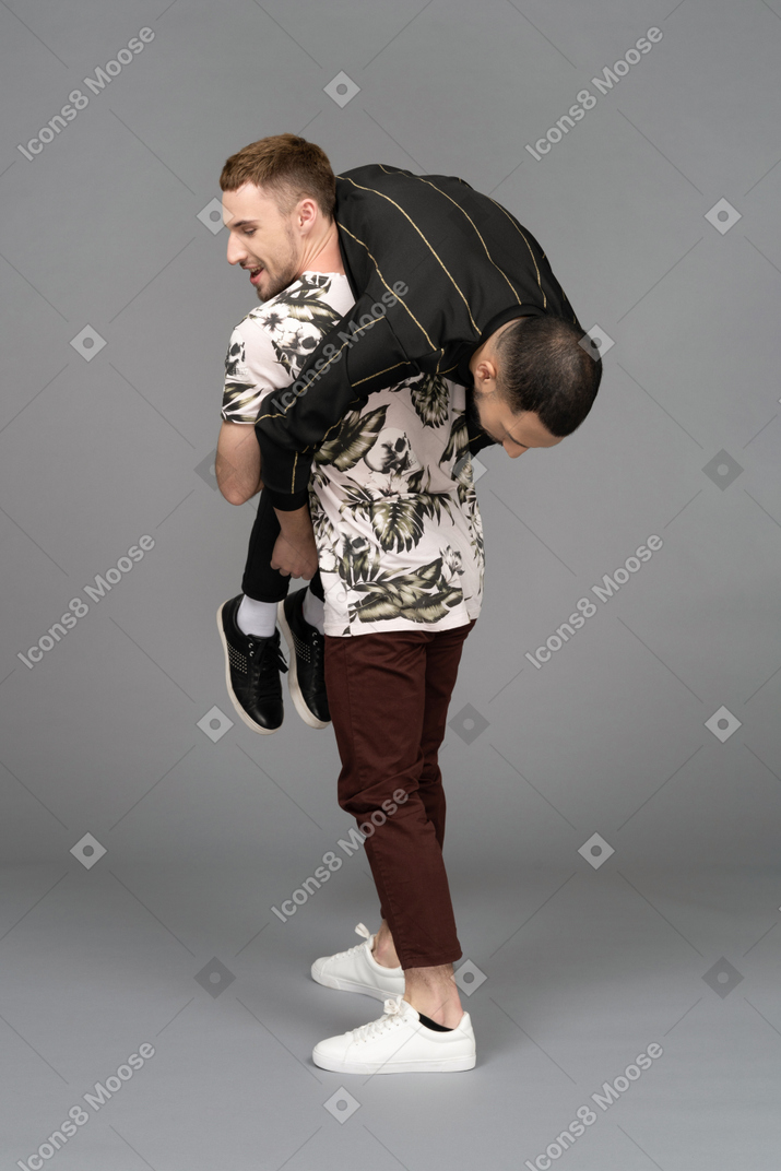 Vue de trois quarts arrière d'un jeune homme en tenant un autre sur son épaule