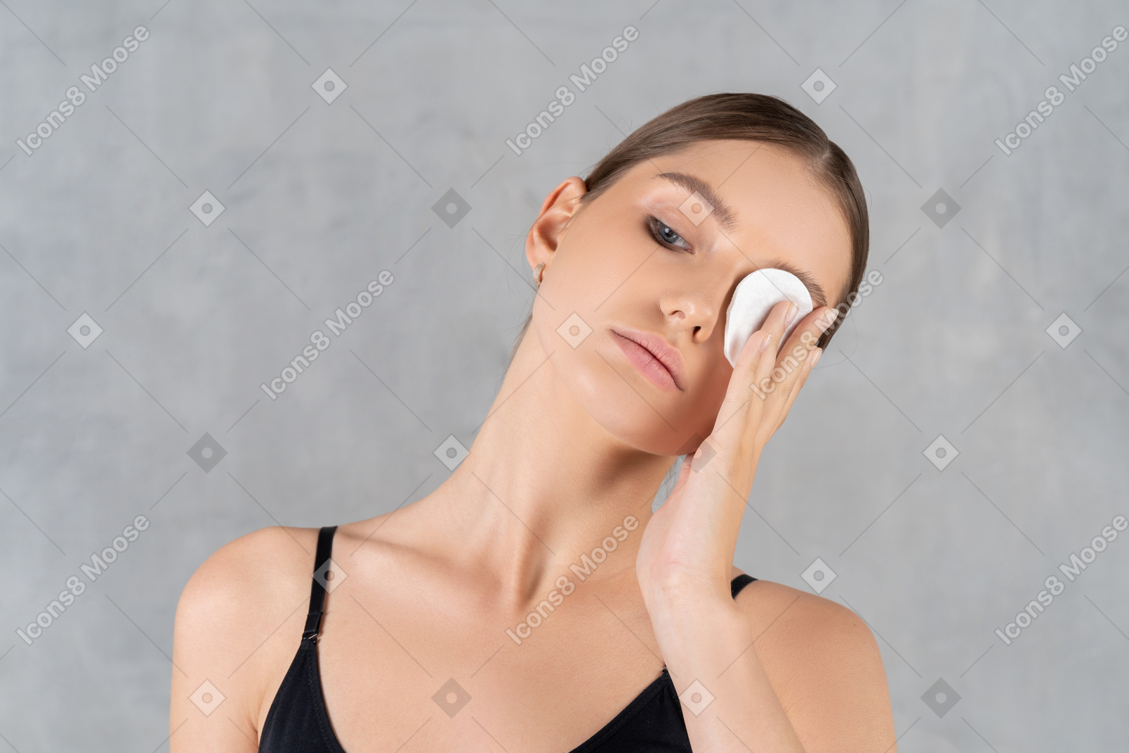 Молодая привлекательная женщина снимает макияж с глаз ватным диском