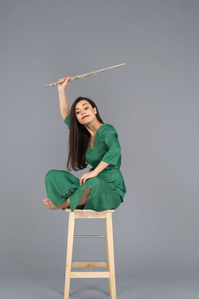 Three-quarter view of a crazy clarinet player sitting on a chair with her legs crossed