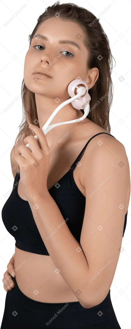 Vista di tre quarti di una giovane donna che si massaggia il viso con un rullo facciale