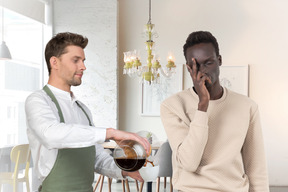 A barista pouring a cup of coffee for a tired man