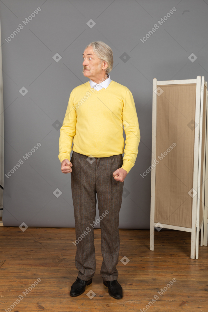 Front view of a strong old man clenching fists while looking aside