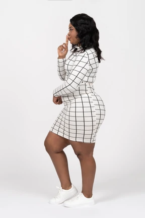 Side view of a young woman in casual clothes making a shhh gesture
