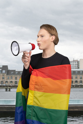 A woman holding a megaphone and a rainbow flag