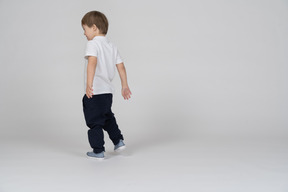 Little boy walking with his arms outstretched behind him
