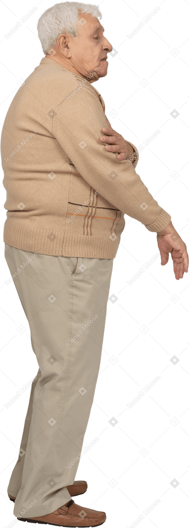 Vista lateral de un anciano con ropa informal de pie con la mano en el brazo
