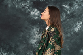 Side portrait of relaxed businesswoman in silk jacket raising head