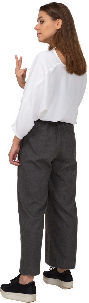 Three-quarter back view of a young lady in office clothing showing two fingers