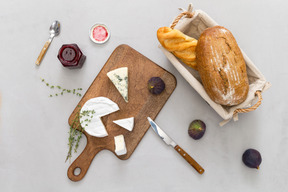 Tabla de cortar con baguette y queso, peras y mermelada.