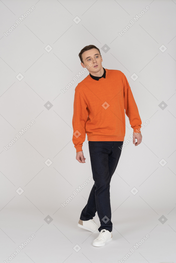 Young man in orange sweatshirt walking