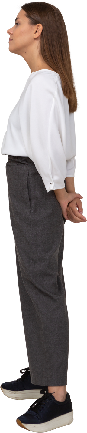 Side view of a young lady in office clothing holding hands behind