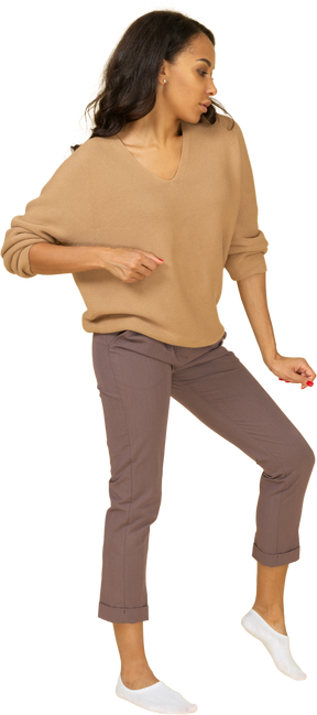 Vista frontal de una mujer joven de piel oscura bailando doblando la rodilla