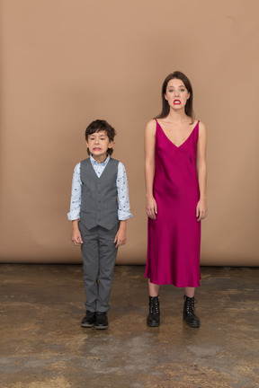 Front view of a grinning boy and woman in red dress