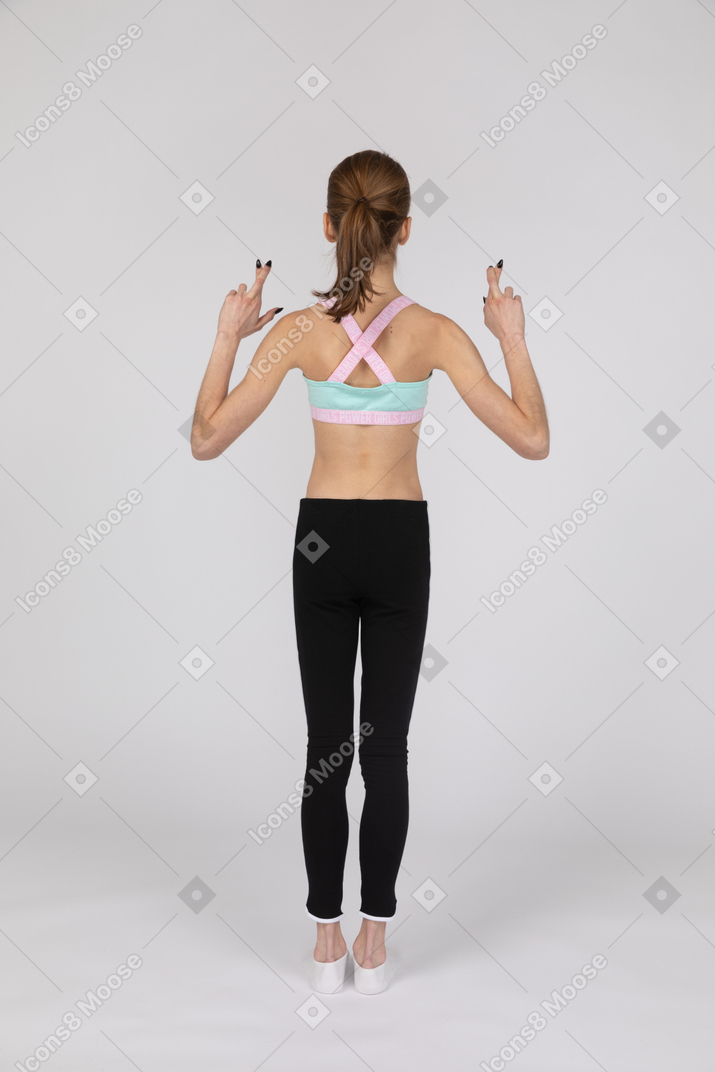 Back view of a teen girl in sportswear crossing fingers