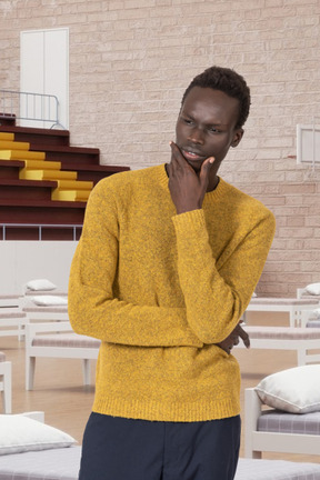A man in a yellow sweater standing in a basketball court with beds