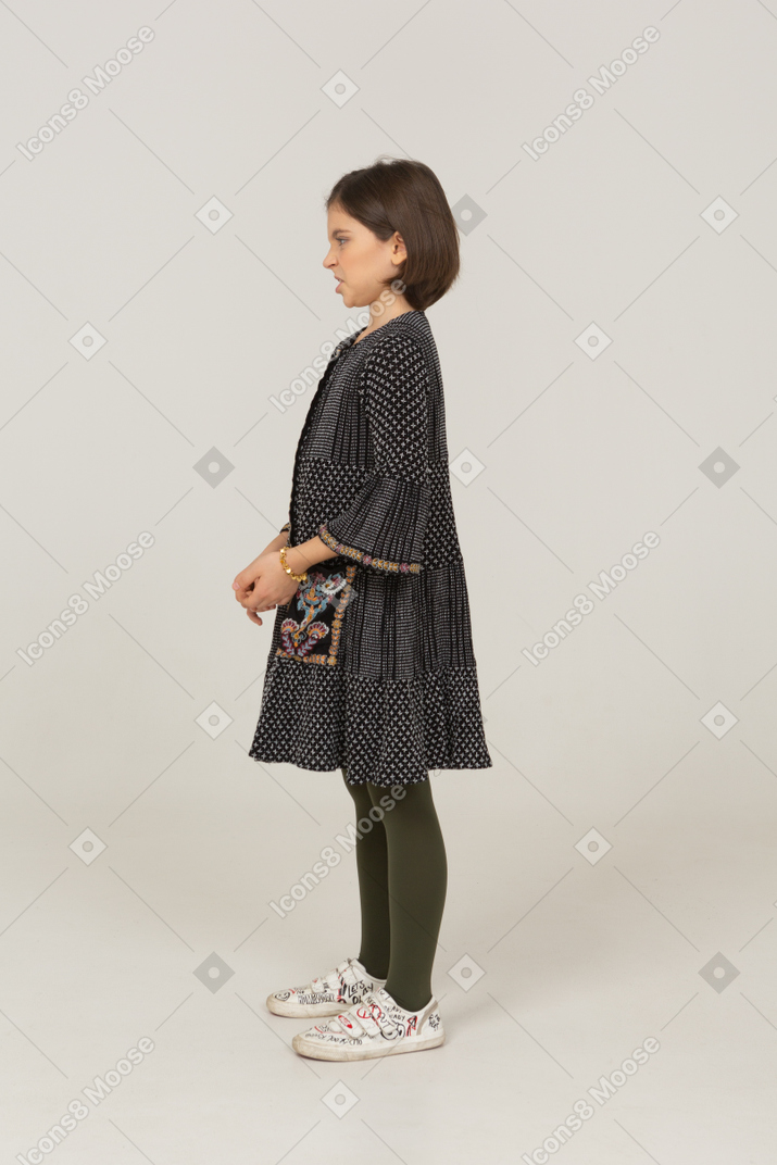 Side view of a grimacing displeased little girl in dress