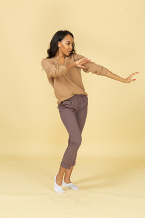 Vista di tre quarti di una giovane femmina danzante gesticolante dalla pelle scura