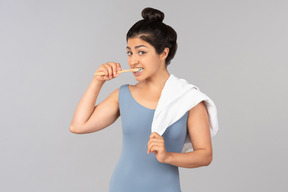 彼女の肩にタオルを押しながら歯を磨く若いインド人女性