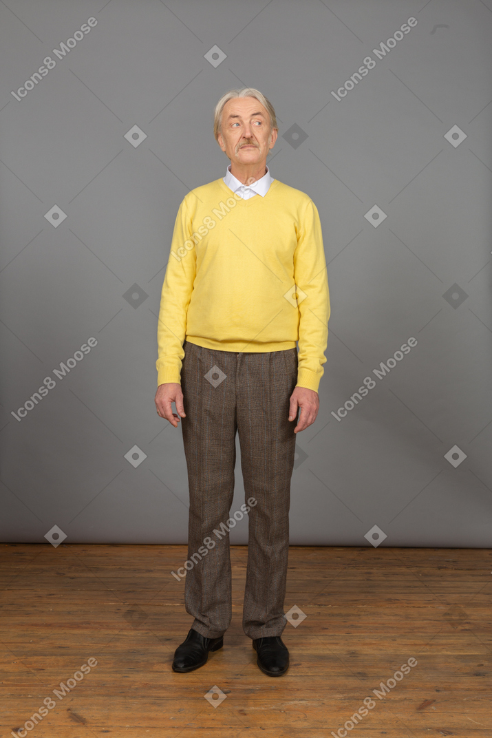 Vorderansicht eines alten neugierigen mannes im gelben pullover, der beiseite schaut