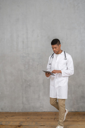 Male doctor looking at tablet while walking