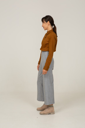 Side view of a winking young asian female in breeches and blouse