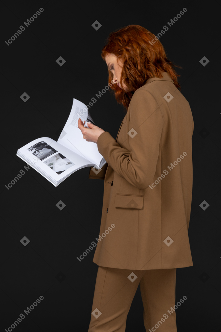Frau im braunen anzug, die zeitschrift durchblättert