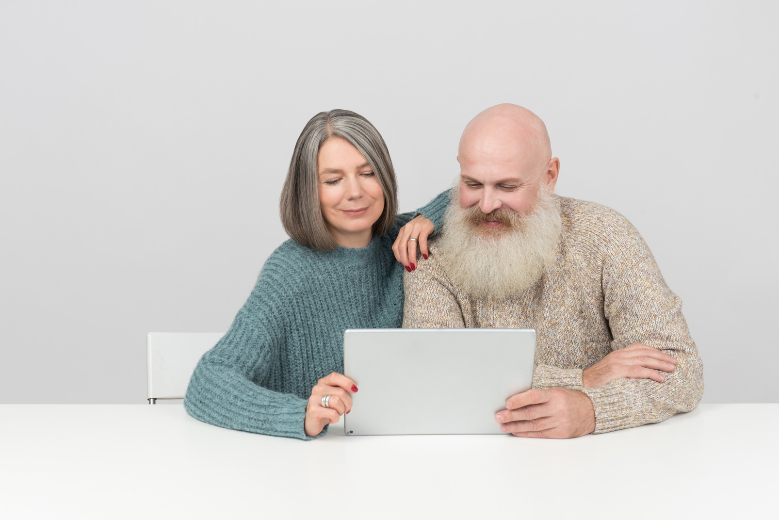 Smiling aged couple looking on something on tablet