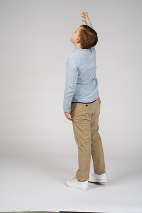 Vista lateral de um menino olhando para cima e acenando