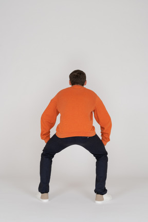オレンジ色のスウェットシャツのポーズで若い男