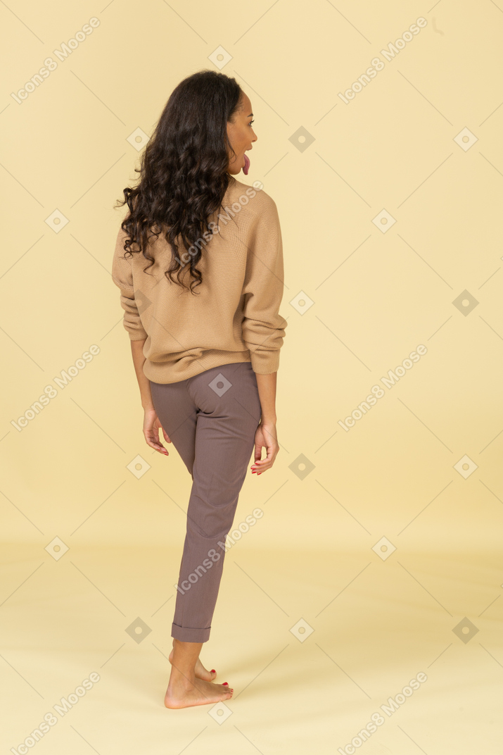 Back view of a young female in casual clothes showing tongue
