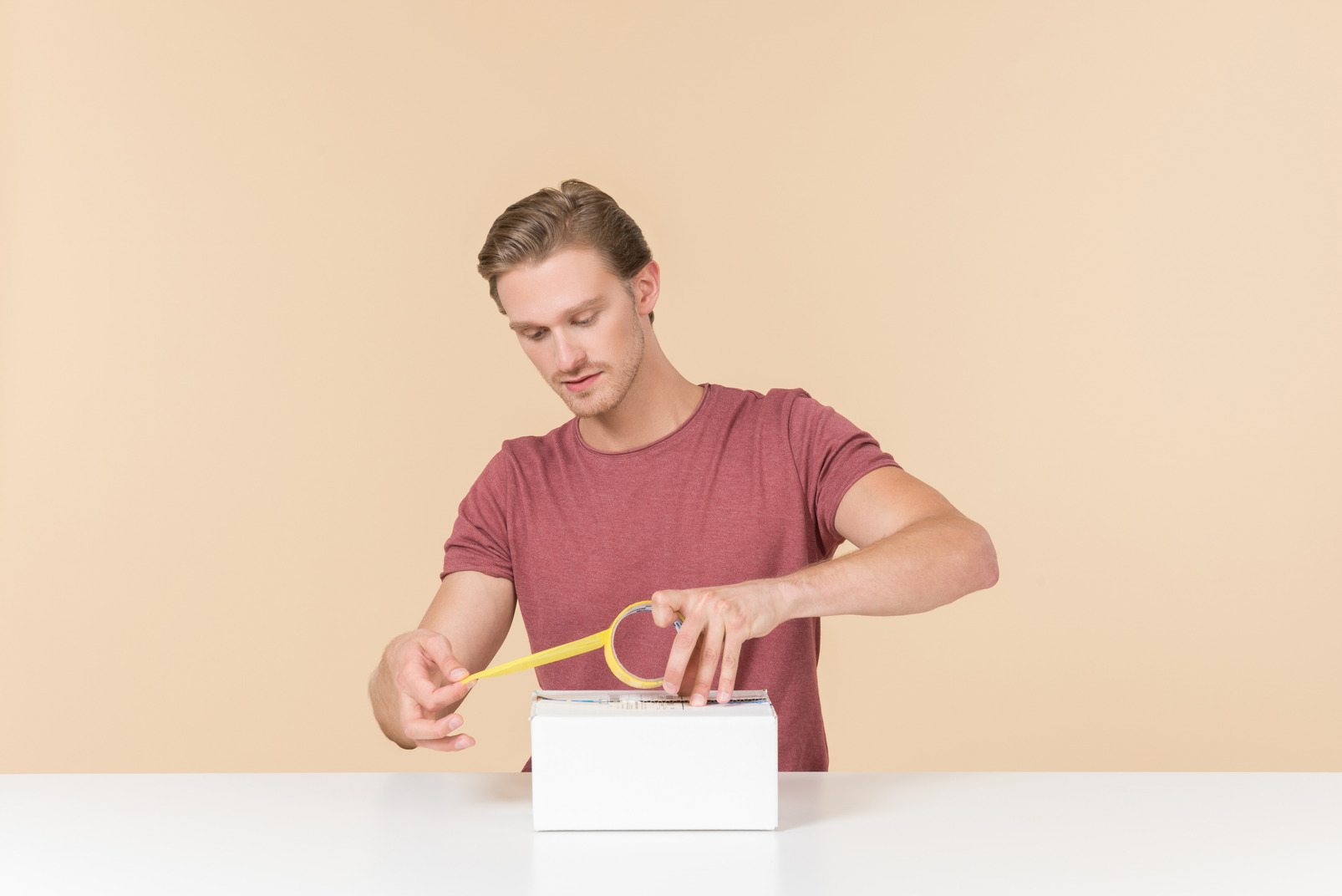 Young guy sitting at the table and closing a box