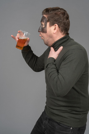 Side view of a surprised male football fan holding a beer