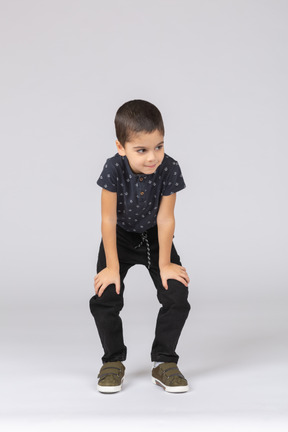 Front view of a cute boy squatting and looking at camera