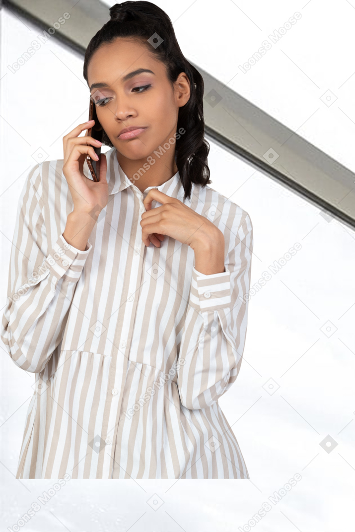 A woman in a striped shirt is talking on a cell phone