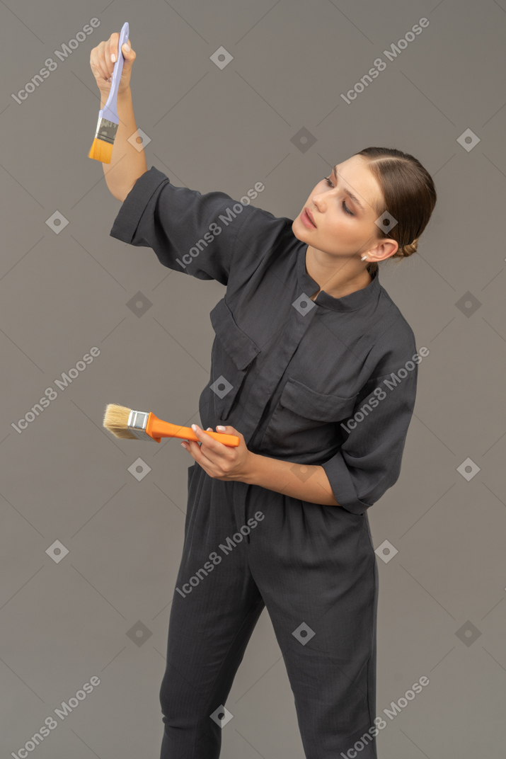 Mujer con overoles grises eligiendo un pincel
