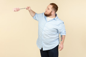 Standing in profile young plump househusband holding pipe-cleaner