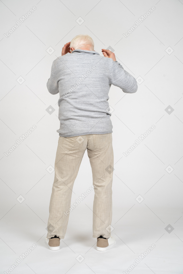 Back view of man reaching for the head with both hands