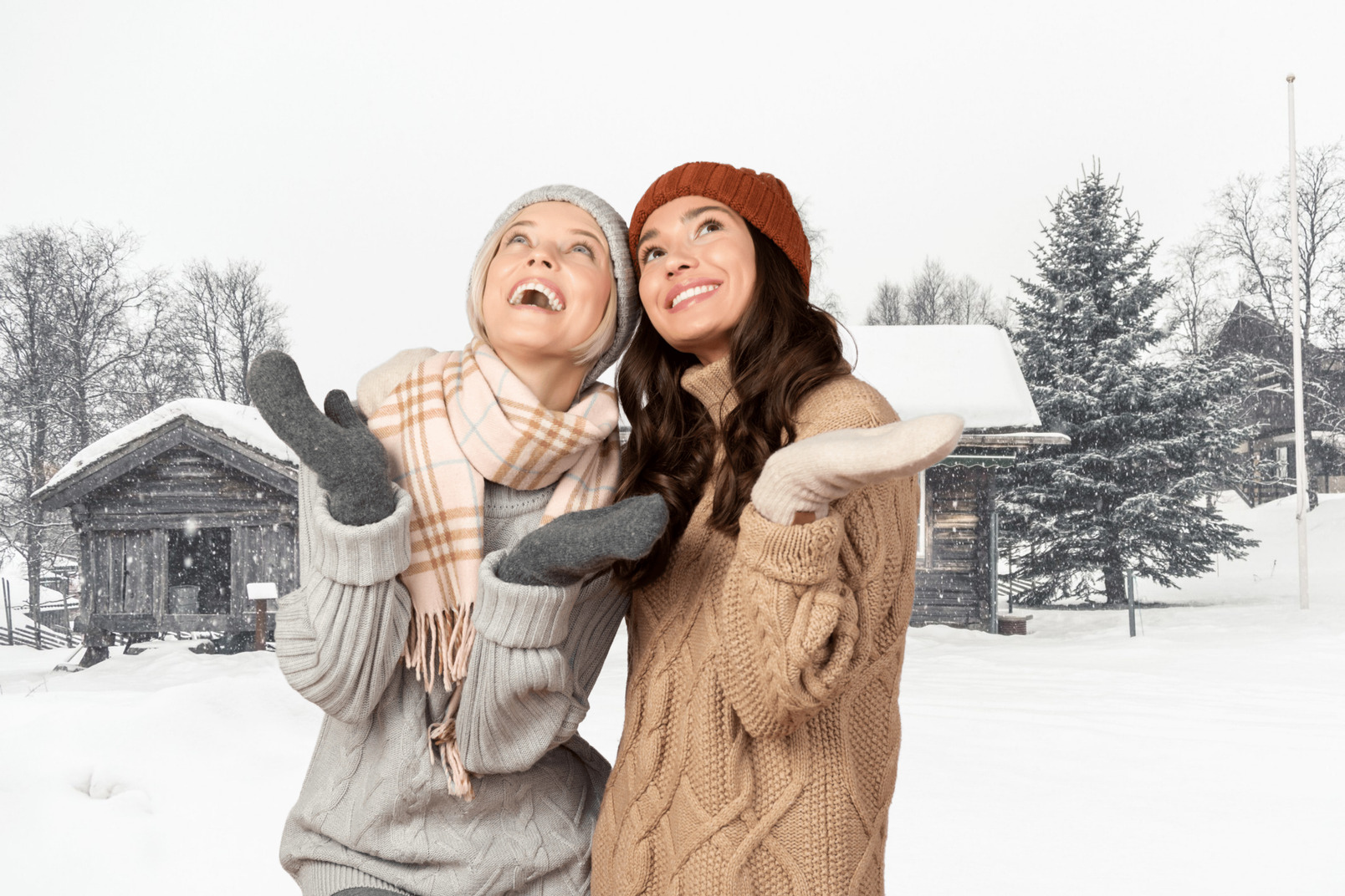 Two women standing outside and catching snowflakes