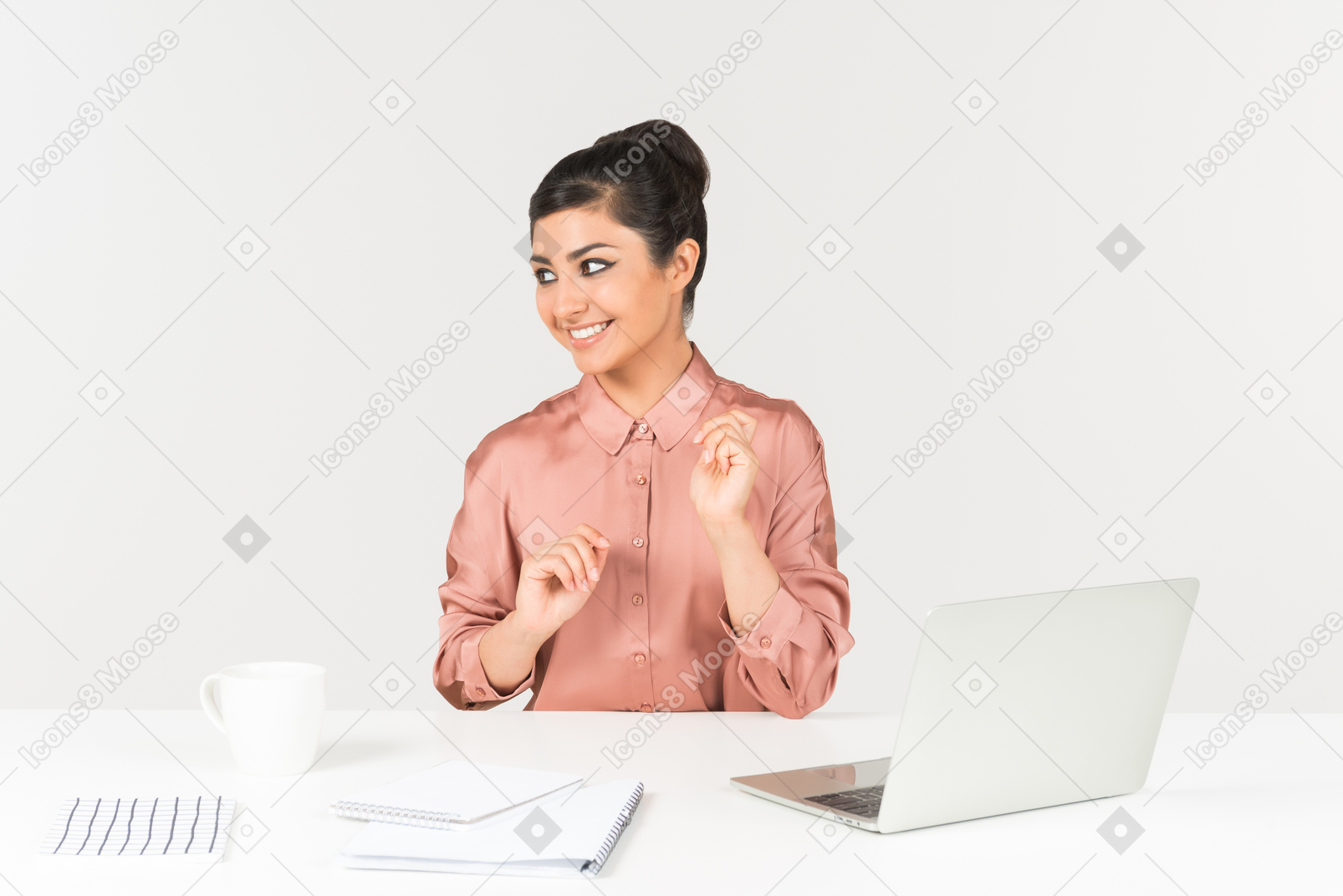Young indian woman sitting at the office desk and looking aside