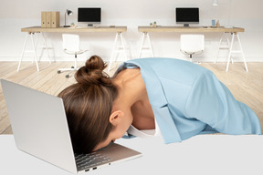 A woman laying her head on a laptop